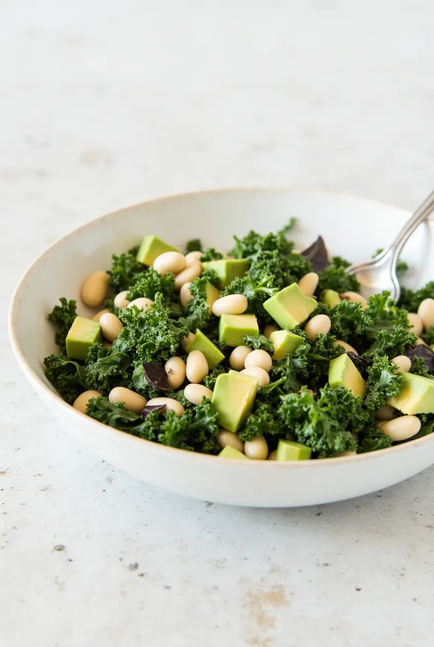 A colorful kale and white bean salad with avocado slices and a lemony dressing.