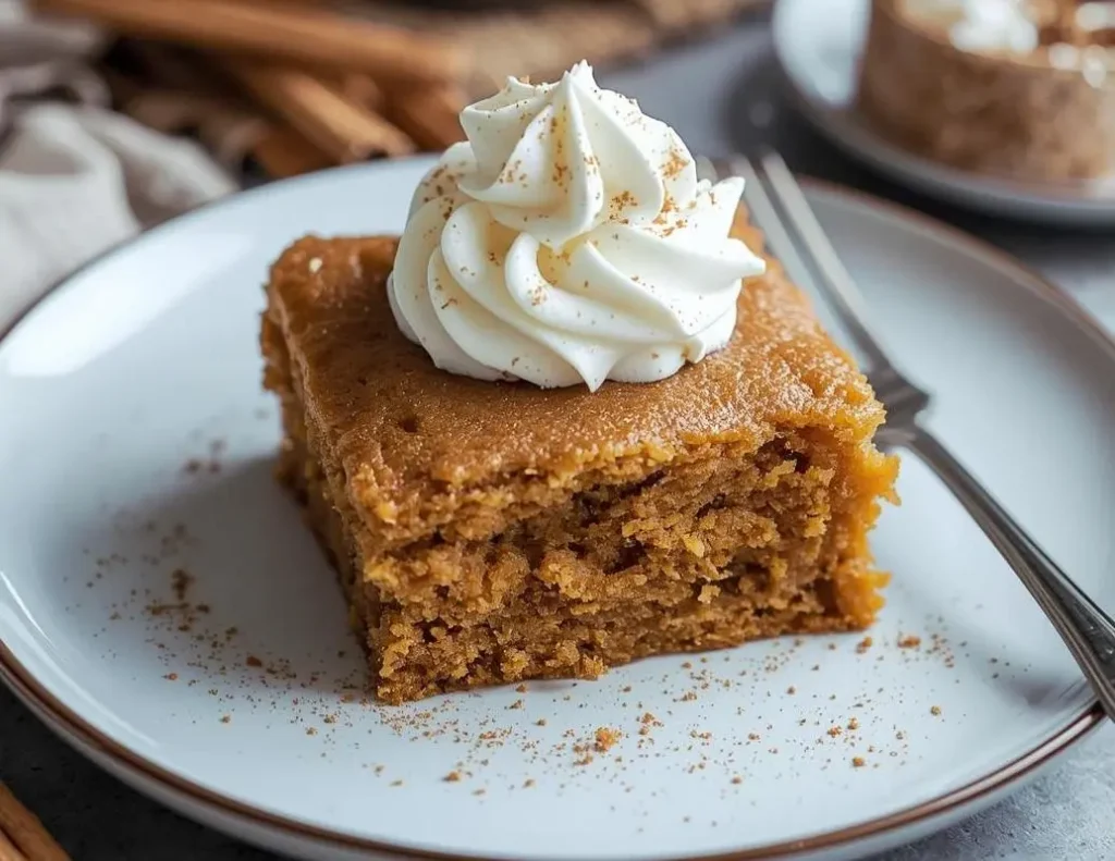 Pumpkin Spice Gooey Cake topped with creamy frosting and a sprinkle of cinnamon sugar
